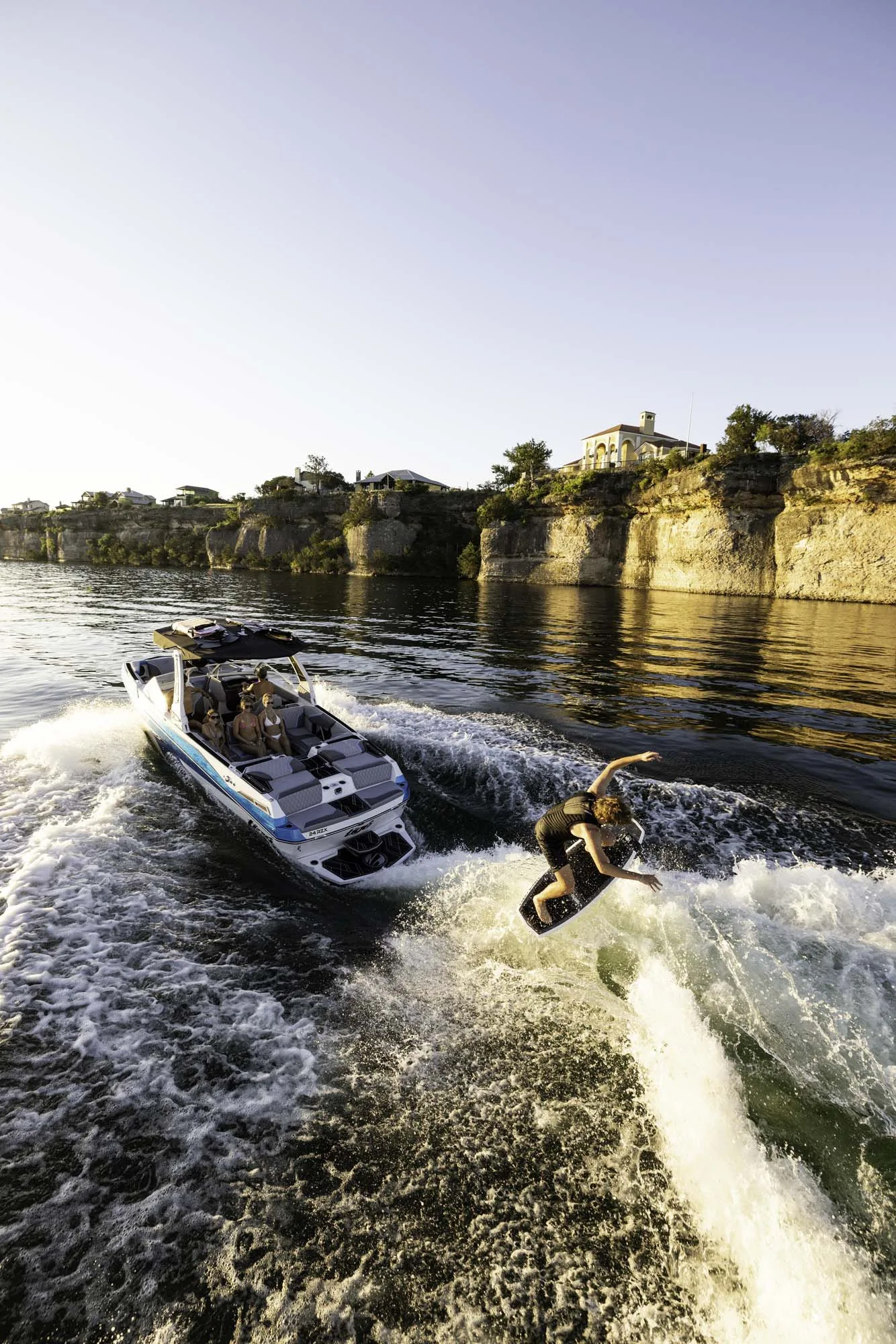 Wake surfing near cliffs at sunset