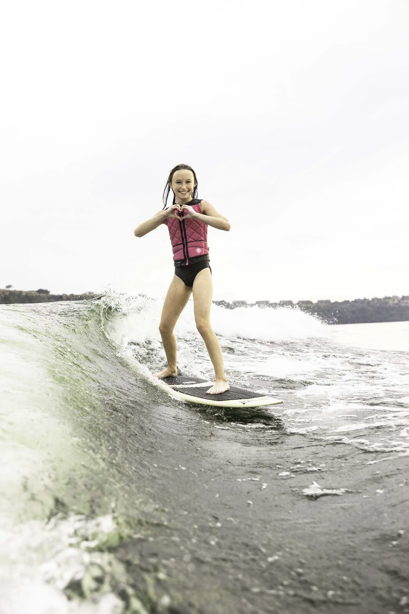 Girl making heart shape while wake surfing